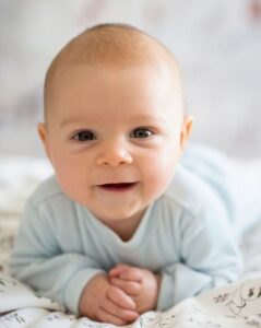 Baby kijkt lachend in de camera.